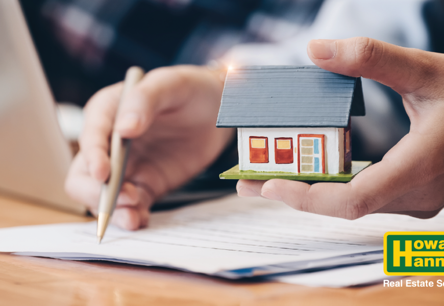 a person holds a model house while budgeting